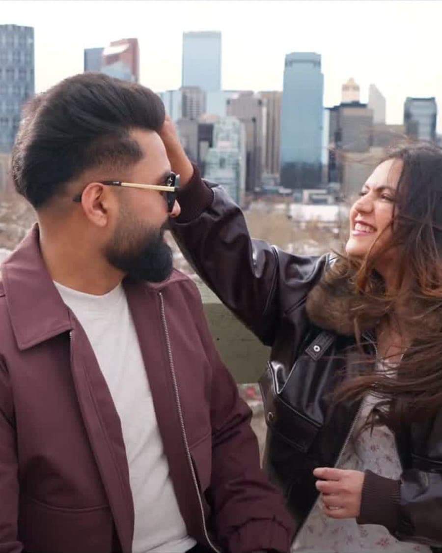 Couple laughing together against the Calgary skyline during a pre-wedding film