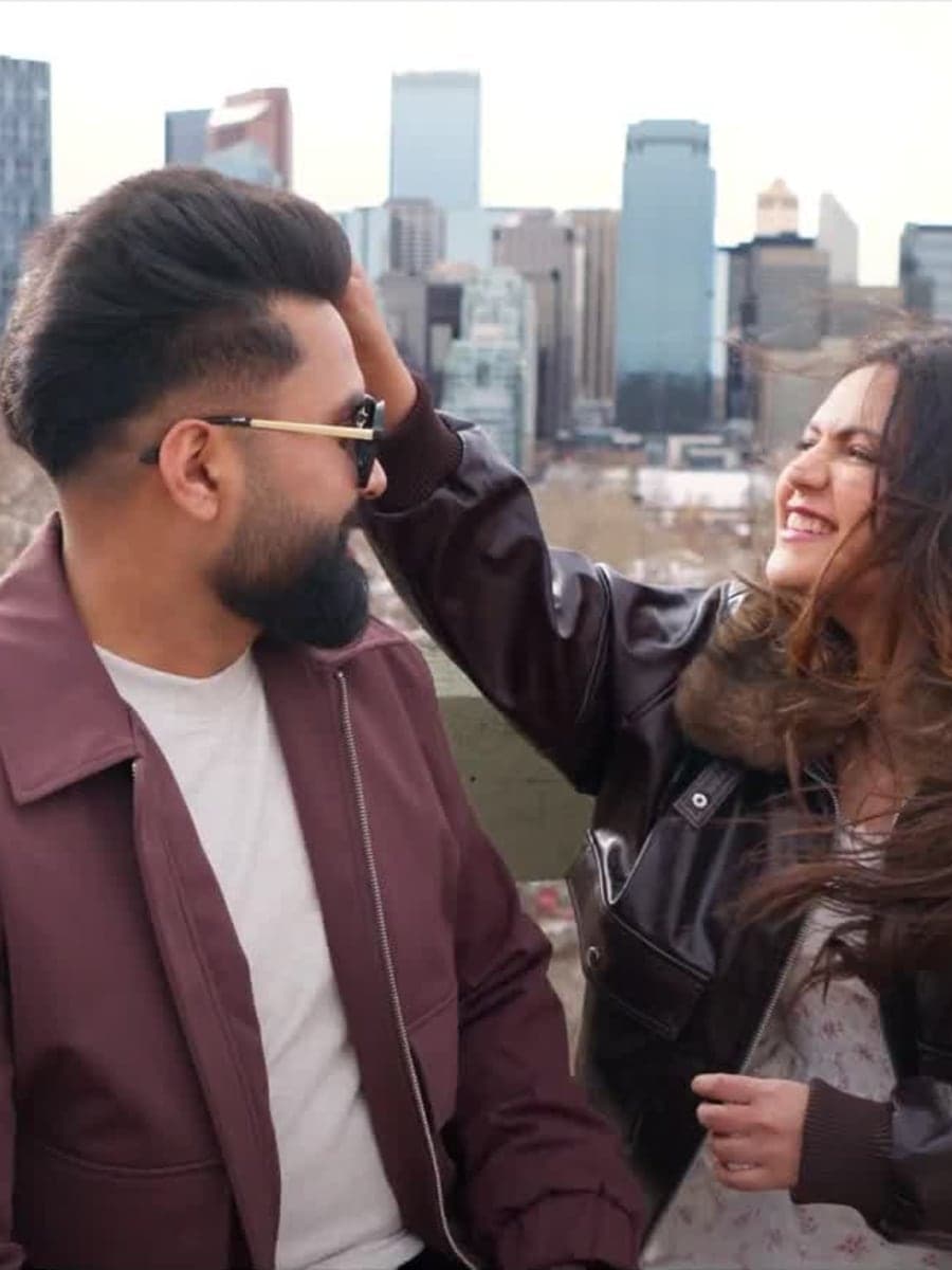 Couple laughing together against the Calgary skyline during a pre-wedding film